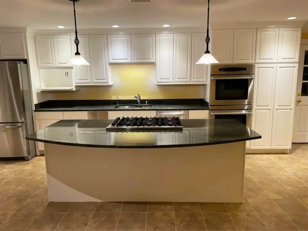 A kitchen with freshly painted white cabinets and a curved island