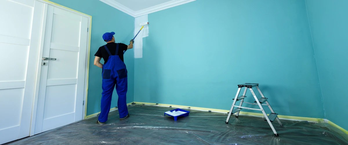 A painter rolling a fresh teal coat onto an interior wall