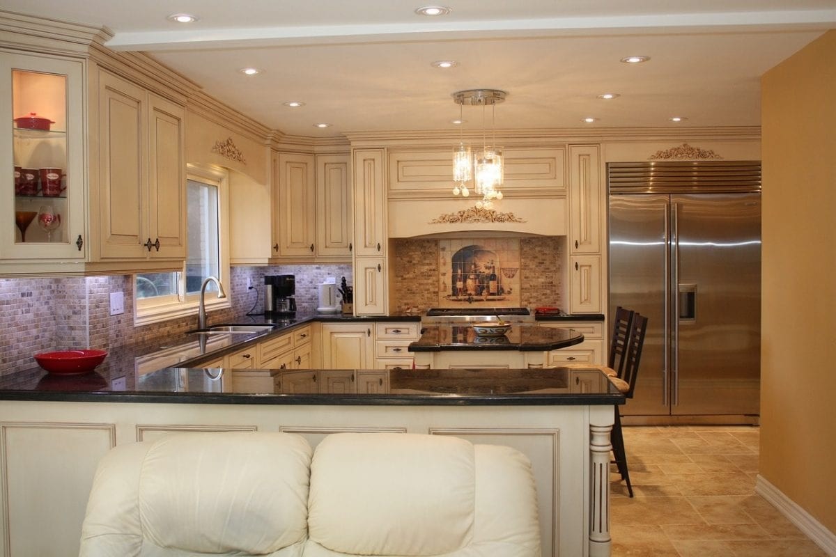 A kitchen with white painted cabinets and a stone backsplash